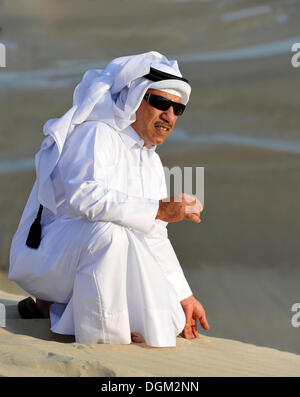 Qatari in traditional clothing with gutra, in front of Khor Al Udeid Beach, Khor El Deid, Inland Sea, desert miracle of Qatar Stock Photo