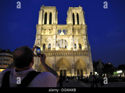 Night shot, western facade of Notre Dame Cathedral, tourist taking a photo of Notre Dame de Paris Cathedral, Ile de la Cité Stock Photo