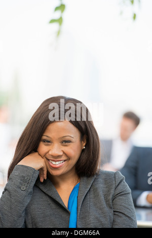 Summer. A woman in a grey suit with a bright blue shirt smiling. Stock Photo