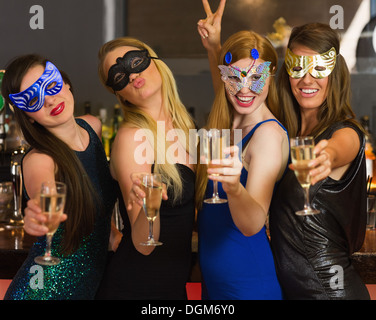 Happy friends wearing masks showing champagne glasses Stock Photo