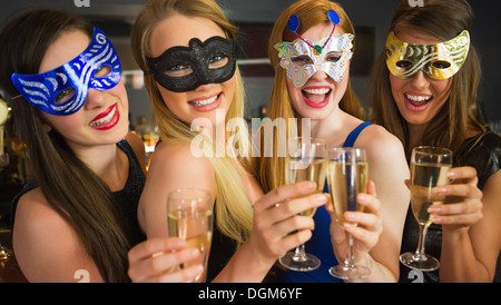 Smiling friends holding champagne glasses wearing masks Stock Photo