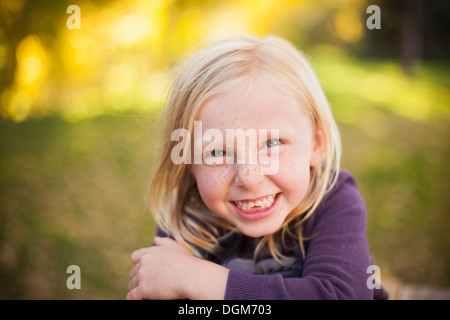 A girl sitting on the grass, smiling a big toothy smile. Close up. Stock Photo