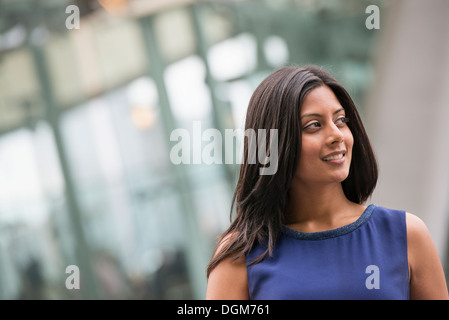 Business people. A woman with long black hair wearing a blue dress. Stock Photo