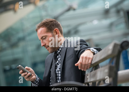 Business people. A man in a business suit. A man with short red hair and a beard, wearing a suit, on his phone. Stock Photo