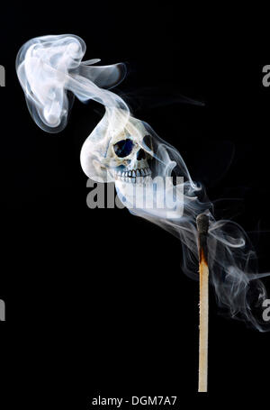 Smoke from a match with a skull, symbolic image for danger due to fire Stock Photo