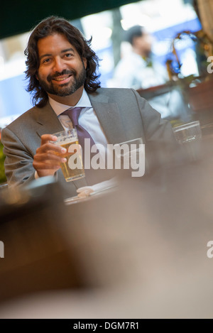 Business people. A Latino man seated at a table in a bar or cafe. Stock Photo