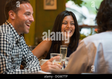 Business people. Three people seated around a table in a bar or cafe, having drinks. Stock Photo
