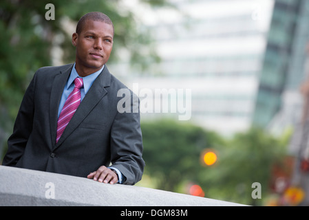 A young man in a business suit with a blue shirt and red tie. On a city street. Stock Photo