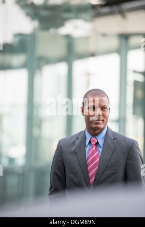 A young man in a business suit with a blue shirt and red tie. On a city street. Stock Photo