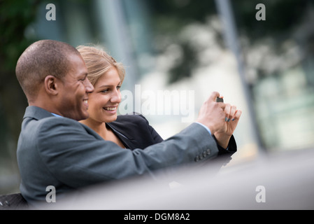 A young blonde woman man on New York city street Wearing business clothes Standing side by side taking selfy photograph smart