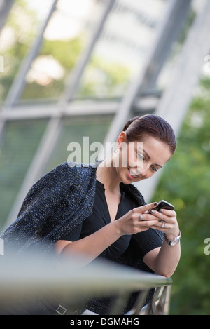 Business people. A woman in a grey jacket with her hair up, using a phone. Stock Photo
