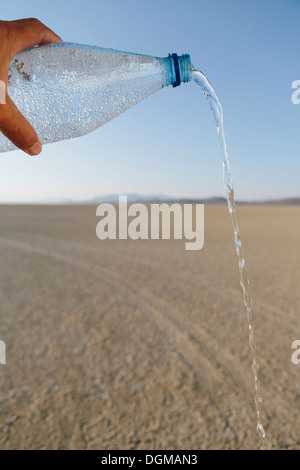 The landscape of the Black Rock Desert in Nevada. A bottle of water being poured out. Filtered mineral water. Stock Photo