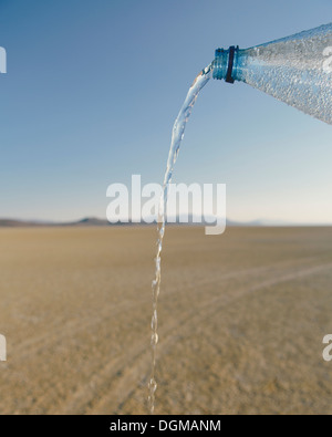 The landscape of the Black Rock Desert in Nevada. A bottle of water being poured out. Filtered mineral water. Stock Photo