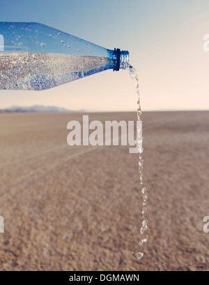 The landscape of the Black Rock Desert in Nevada. A bottle of water being poured out. Filtered mineral water. Stock Photo