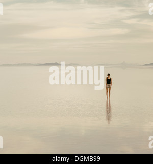 Woman standing on the flooded Bonneville Salt Flats, at dusk. Stock Photo