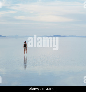 A woman standing on the flooded Bonneville Salt Flats, at dusk. Stock Photo