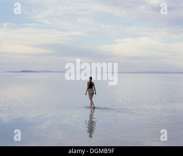 A woman standing on the flooded Bonneville Salt Flats at dusk. Reflections in the shallow water. Stock Photo