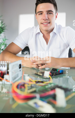 Attractive computer engineer sitting at desk looking at camera Stock Photo
