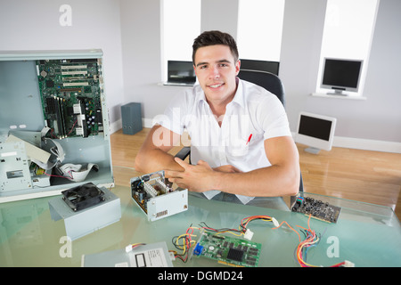 Nice looking computer engineer sitting at desk smiling at camera Stock Photo