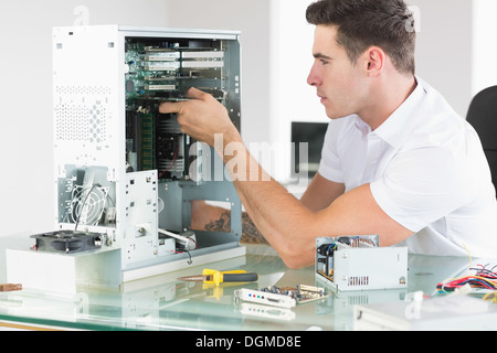 Handsome unsmiling computer engineer working at open computer Stock Photo