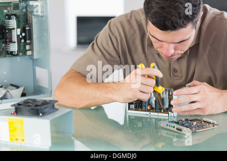 Handsome frowning computer engineer repairing hardware with pliers Stock Photo