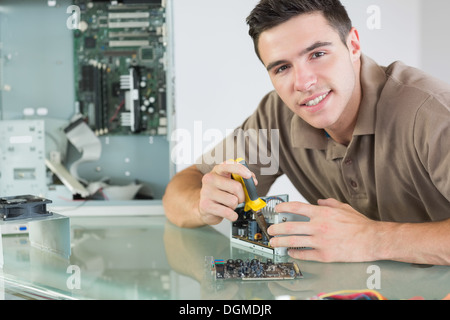Handsome smiling computer engineer repairing hardware with pliers Stock Photo