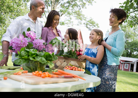 Family party. A table laid with salads and fresh fruits and vegetables. Parents and children. Stock Photo