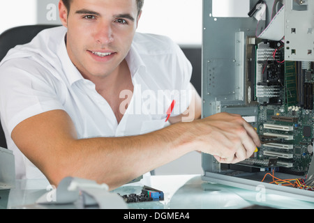 Smiling computer engineer repairing computer with pliers Stock Photo