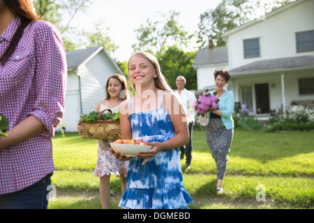 Family party. Parents and children carrying flowers, fresh picked vegetables and fruits. Preparing for a party. Stock Photo