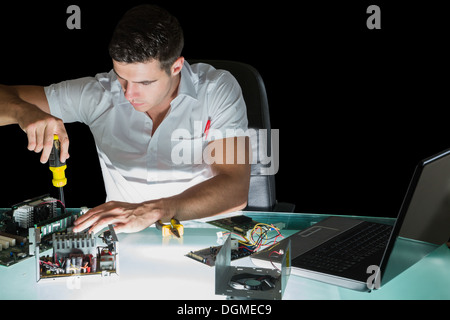 Handsome stern computer engineer working by night with screw driver Stock Photo