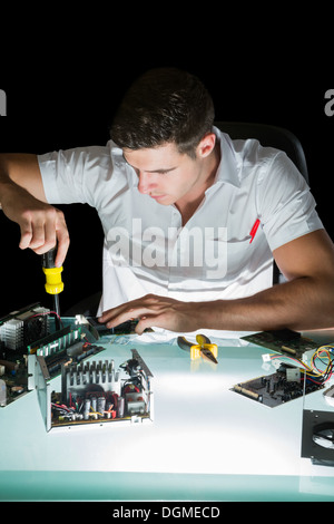 Handsome computer engineer working by night with screw driver Stock Photo