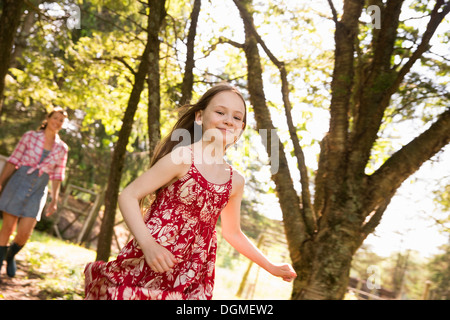 A woman and a young girl running along through the trees. Stock Photo