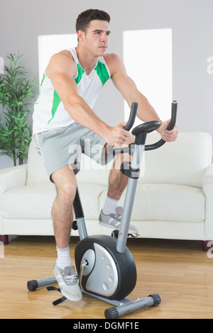 Determined handsome man training on exercise bike Stock Photo