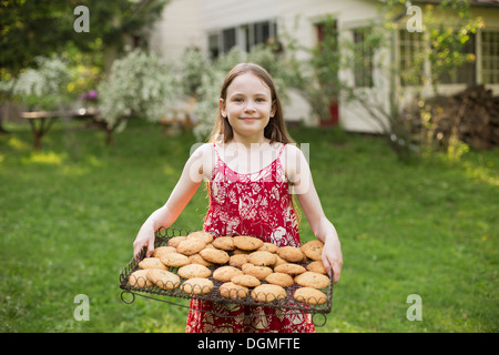 Baking homemade cookies. A young girl holding a tray of fresh baked cookies. Stock Photo