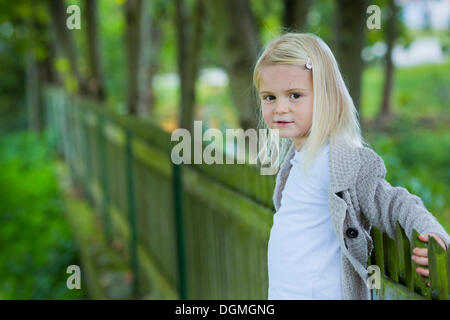 Girl, 4 years old, leaning against a wooden fence Stock Photo