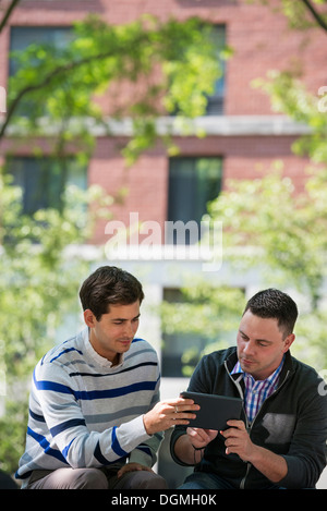 Summer. Business people. Two men sitting using a digital tablet. Stock Photo