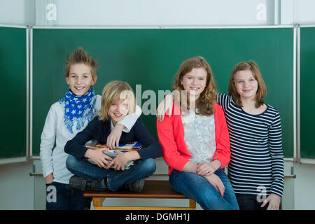 Four smiling schoolchilden in the classroom, Germany Stock Photo