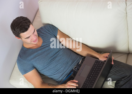 Overhead view of attractive man relaxing on couch using laptop Stock Photo