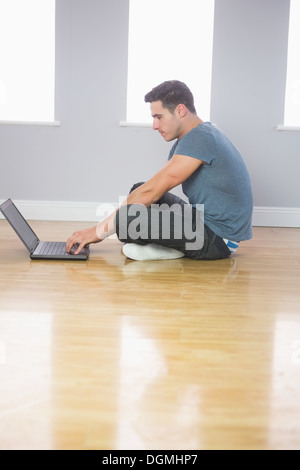 Focused handsome man using laptop sitting on floor Stock Photo