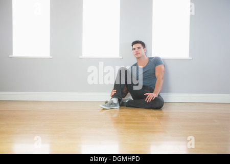 Thinking handsome man leaning against wall sitting on the floor Stock Photo