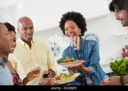 An informal office event. People handing plates of food across a buffet table. Stock Photo