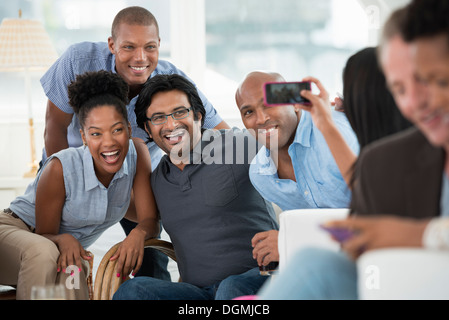 office event. A man taking a selfie of the group with a smart phone. Stock Photo