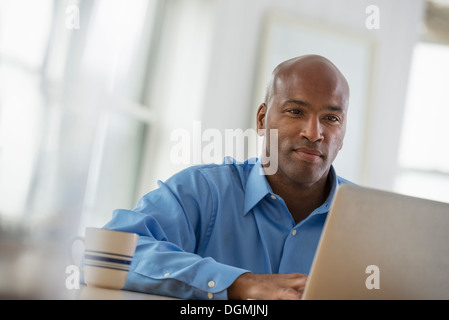 Office. A man sitting using a laptop. Stock Photo