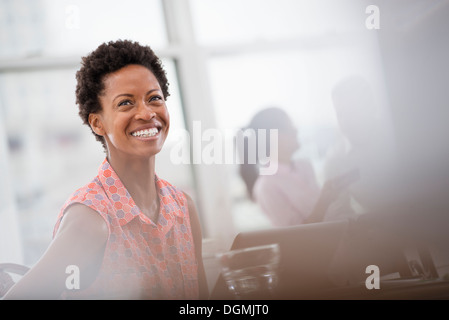 Office life. A young woman in a pink shirt laughing. Stock Photo