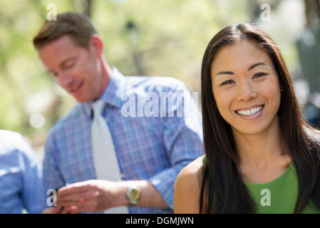 A small group of people, a businesswoman and two businessmen outdoors in the city. Stock Photo