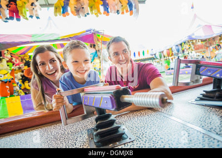 USA, Utah, Salt Lake City, Happy Family with son (4-5) playing with water gun in amusement park Stock Photo