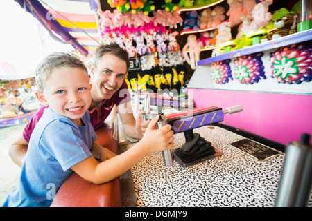 USA, Utah, Salt Lake City, Father with son (4-5) playing with water gun in amusement park Stock Photo