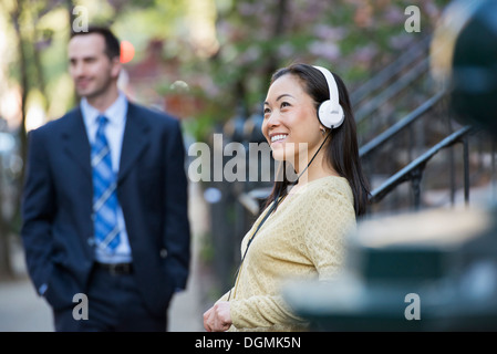 A woman wearing music headphones, and a man in a business suit. Stock Photo