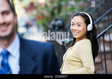 A woman wearing music headphones, and a man in a business suit. Stock Photo