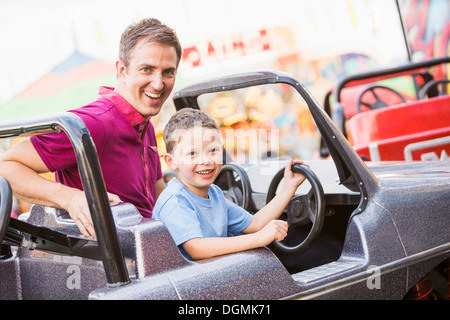 USA, Utah, Salt Lake City, Father with son (4-5) driving toy car in amusement park Stock Photo